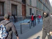 Jóvenes de Ayotzinapa derriban una puerta del Palacio Nacional con López Obrador adentro